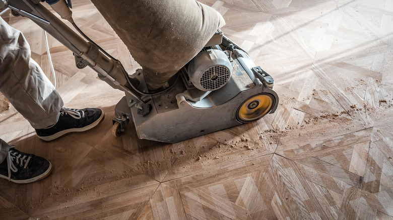 A person sanding parquet wood floors