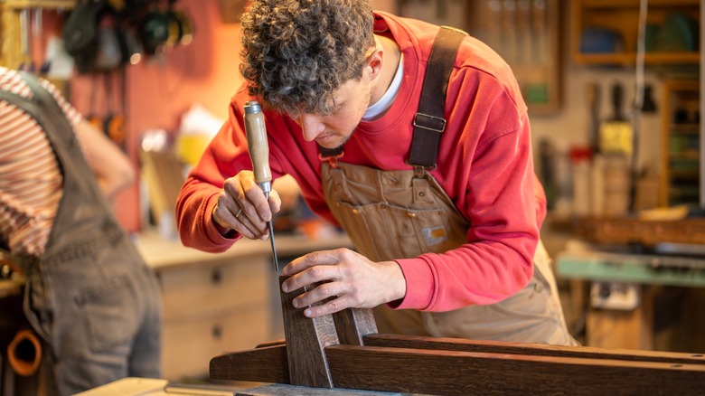 Carpenter working on a dark wood piece of furniture