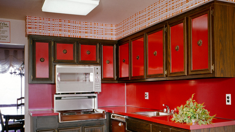 Dark 1970s cabinets with bright red with cabinet knobs in the center of the doors