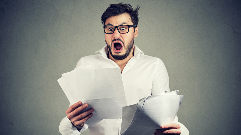 Shocked man holding papers