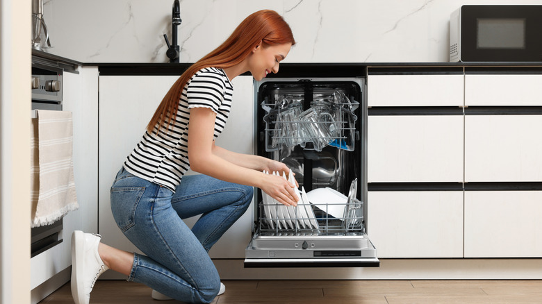 A woman loads a small dishwasher