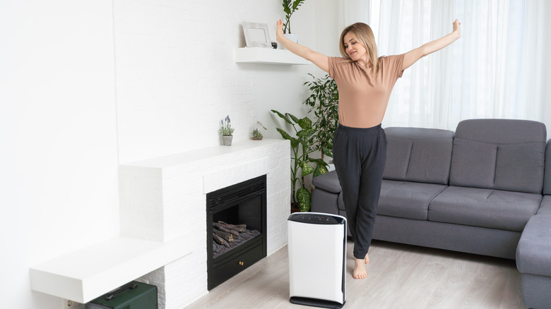 young blonde woman stretching beside dehumidifier in living room