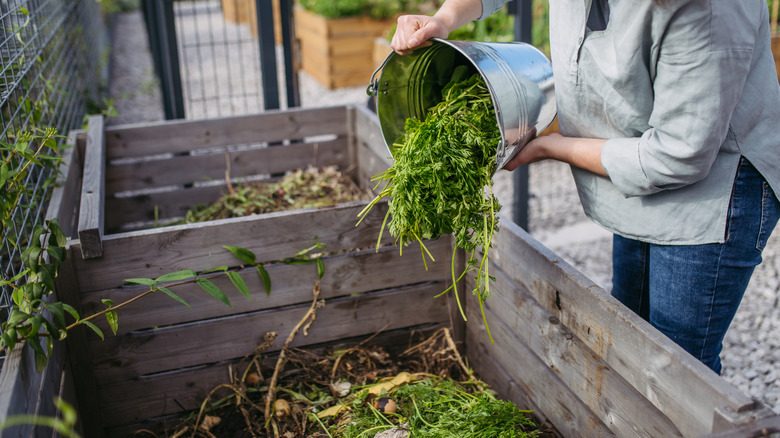 Woman adding leaves to a raised garden bed