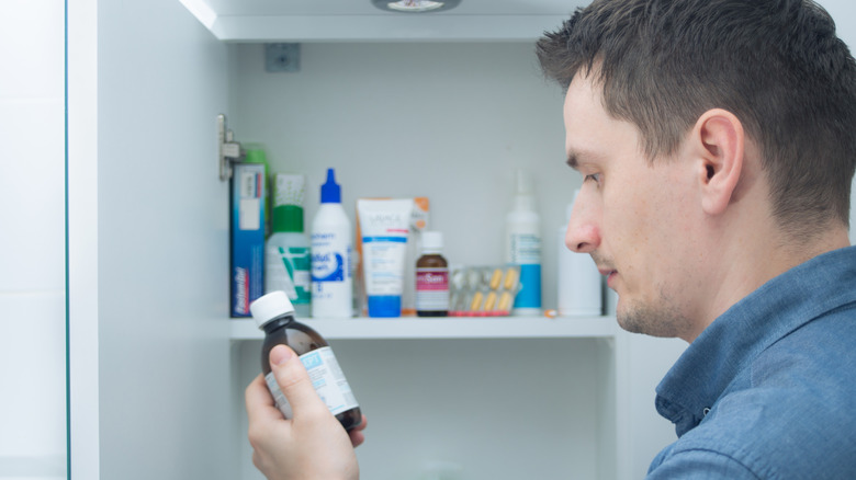 Person taking medicine from cabinet