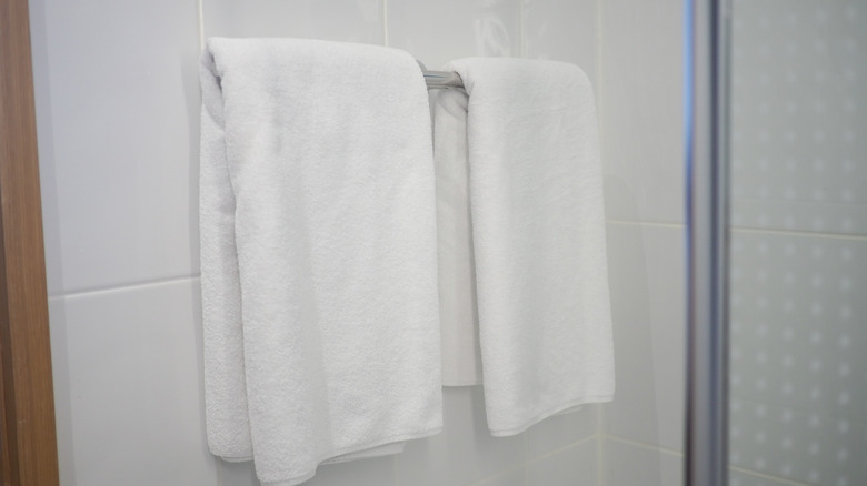 Two white towels hanging from a silver wall-mounted towel bar.