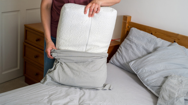 Person putting a pillow in a gray pillowcase