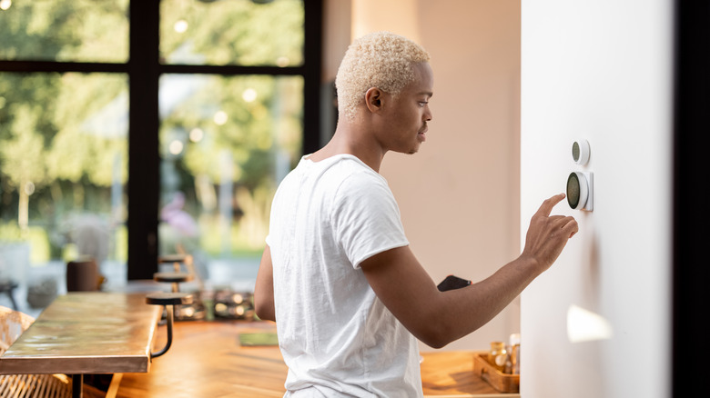 Woman setting home's thermostat