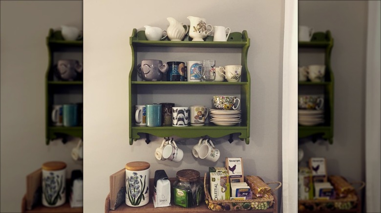 Green curio shelf on wall filled with mugs