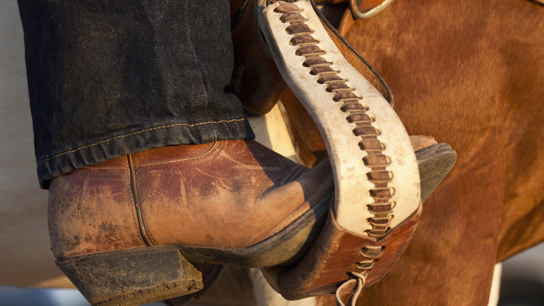 Closeup of a cowboy boot in a stirrup with a horse