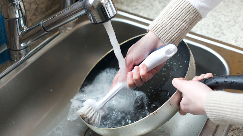 Person washing a metal frying pan