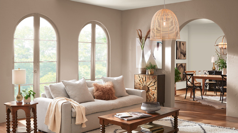 Large arched windows illuminate a living room painted Behr Rodeo Tan
