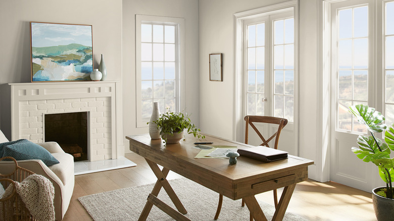 A light-filled office with a fireplace and coastal accents is painted with Behr's White Moderne