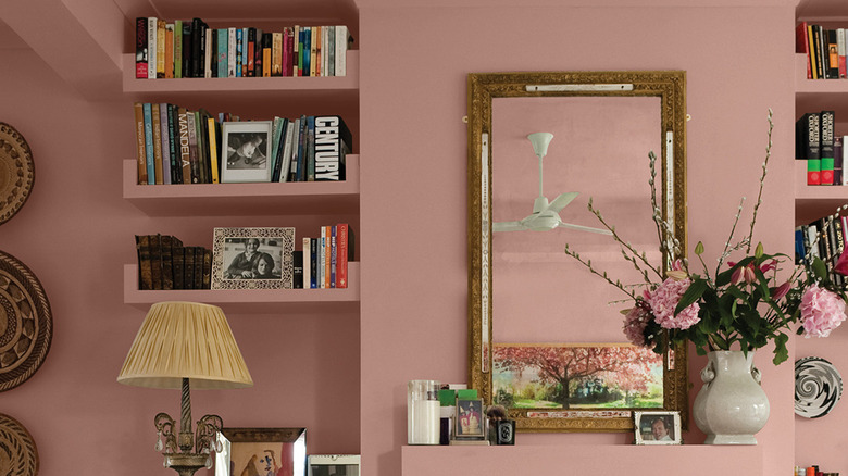 An eclectic display of books, flowers, and small items are in front of a wall painted with Glidden Sandpaper