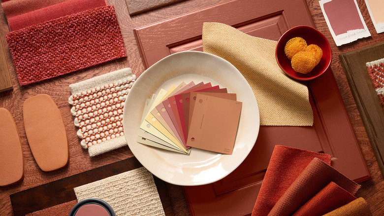 A selection of rusty red paint chips and fabrics are artfully arranged on a table