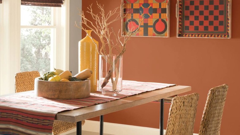 A dining table covered in a woven runner and wooden accents sits in front of a wall painted with Sherwin-Williams Pennywise