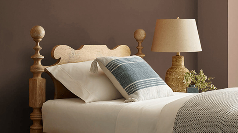 A neatly made bed sits in front of a wall painted Sherwin-Williams Sable
