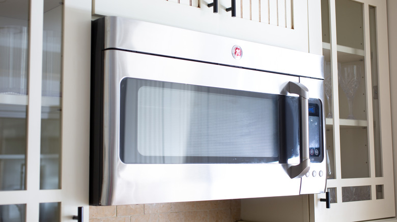 A GE microwave installed above a range in a kitchen