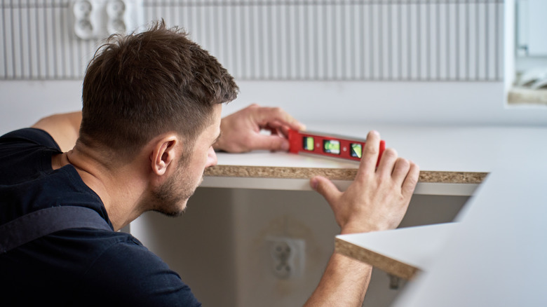 Man using a leveler while installing countertops in kitchen