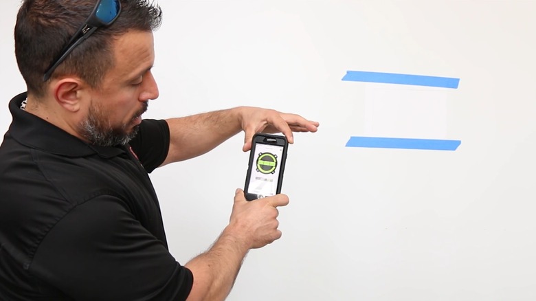 Man holding a smartphone while using a level app