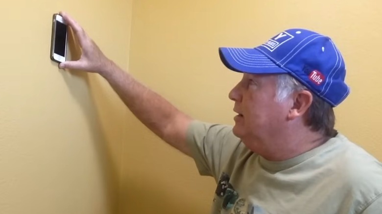 Man using his smartphone with a stud finder app