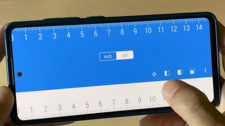Person holding a smartphone with a ruler app displayed