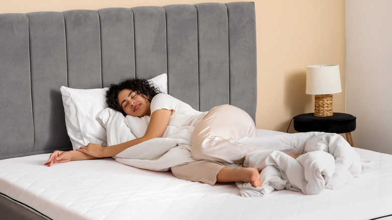 Woman lies comfortably on a bare foam mattress.