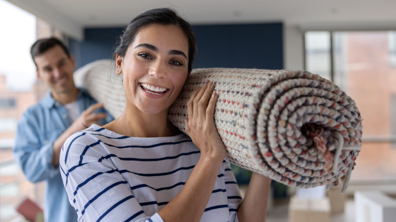 A happy couple carrying a carpet 