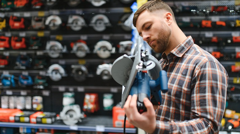 Man looks at corded saw