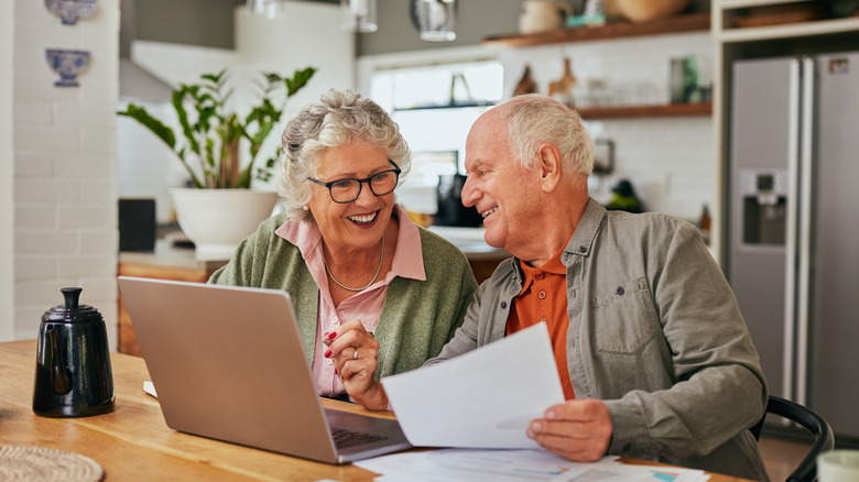 Older white couple in front of a laptop in a modern kitchen.