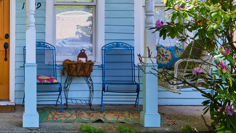 blue house with columns that has blue metal chairs on patio