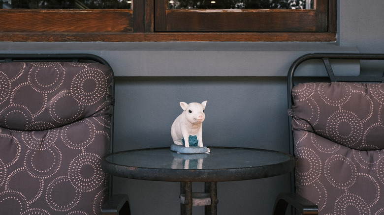 pig figurine on outdoor table next to two brown cushioned chairs