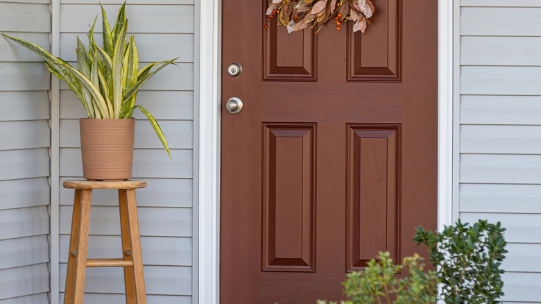 wood stool with beige planter on top next to exterior door