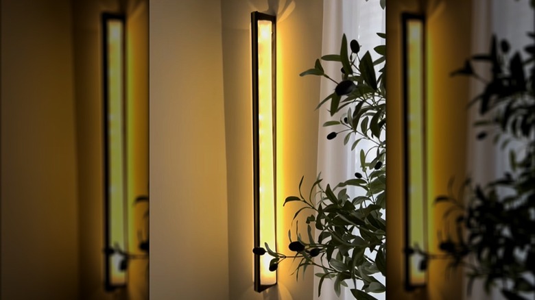 A modern black wall DIY sconce glows with warm light.