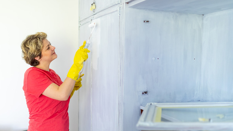 woman priming cabinets