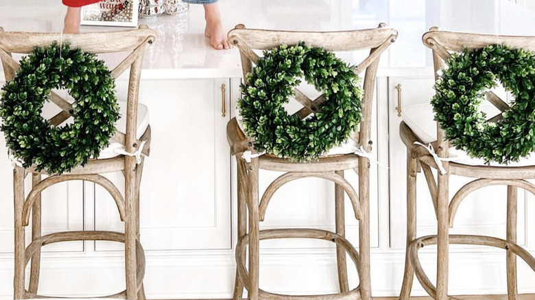 Mini wreaths attacked to the back of kitchen stools.