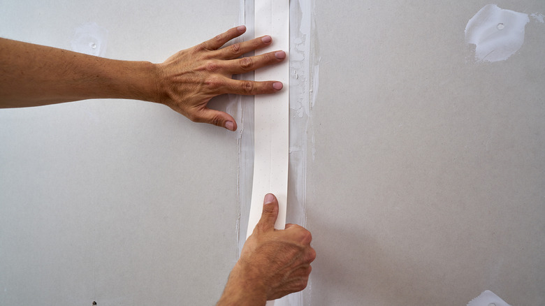 Hands applying drywall tape