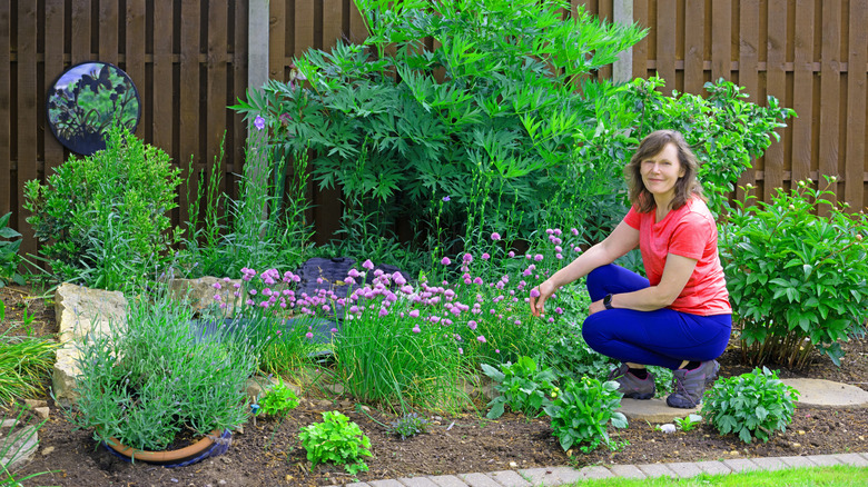 woman planting pollinator garden near fence