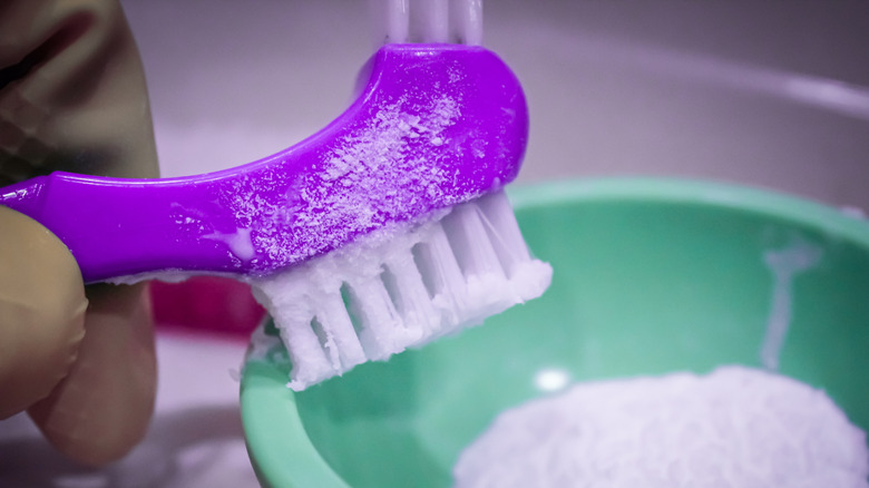 Purple brush mixing baking soda paste for home cleaning