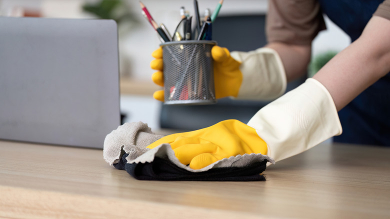 person wiping down desk with rag
