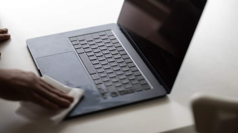 person wiping down laptop keyboard