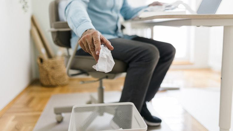 person throwing away trash in home office