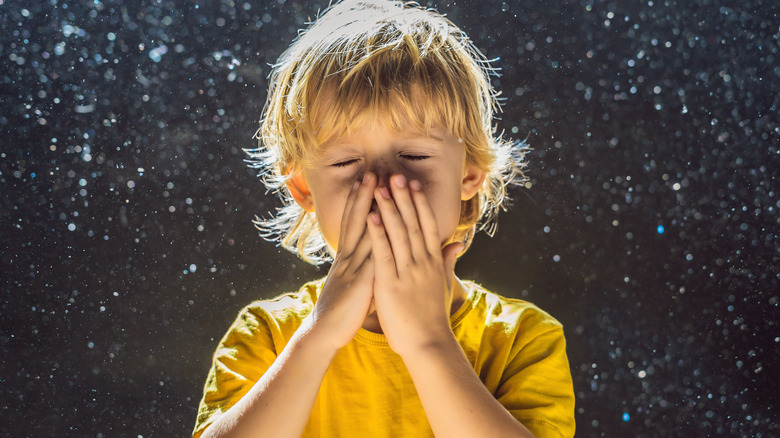 Boy surrounded by dust, sneezing