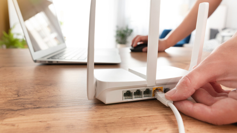 Person connecting a Wi-Fi router on their desk