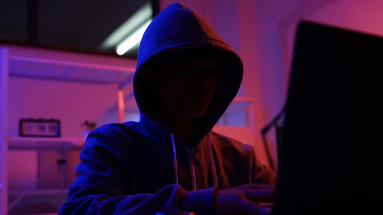 Mysterious hooded hacker in a dark room