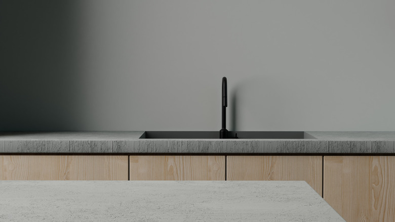 A gray concrete countertop in a contemporary kitchen with wooden cabinets.