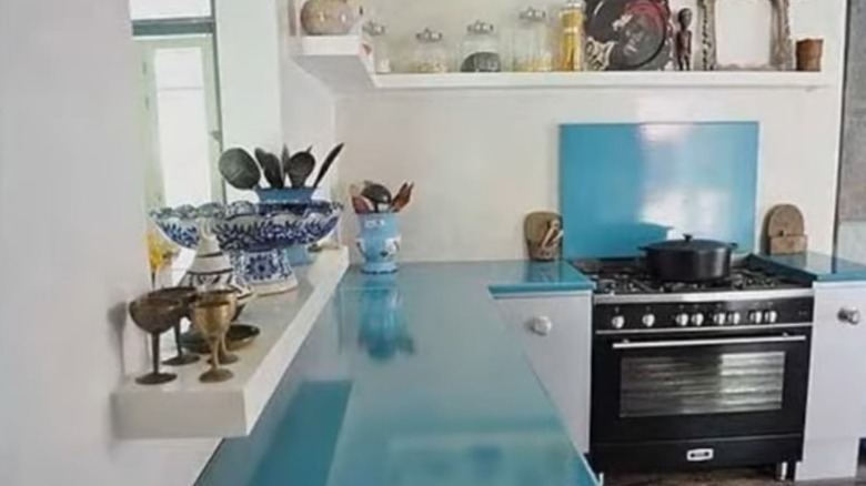 A modern kitchen with blue lava stone counter tops and eclectic personal decorations.