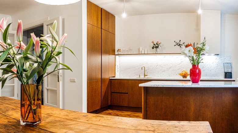 A modern kitchen featuring wooden cabinetry, a marble backsplash, and sleek timber and marble countertops.
