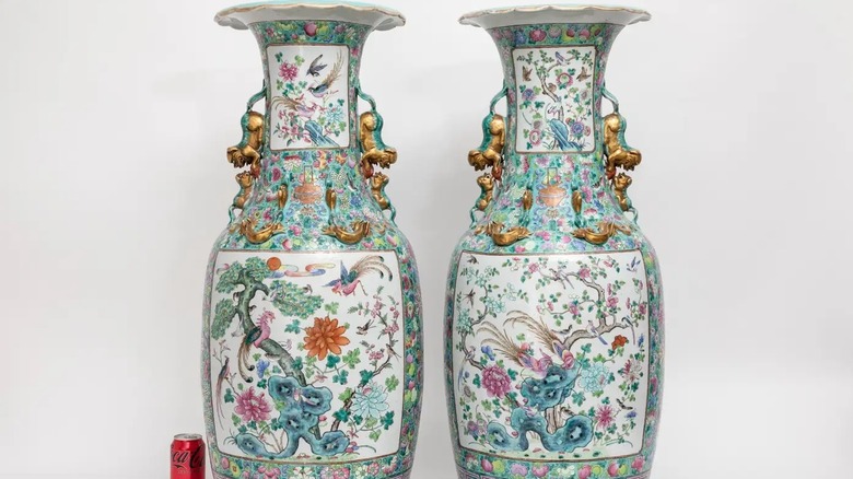 Pair of Qing dynasty Famille Rose vases with foo dog handles next to a can of Coca Cola