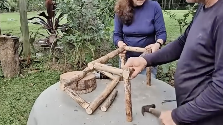 Constructing a frame for a planter of small cut tree branches.