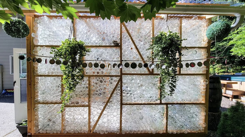 Greenhouse made of upcycled glass jars with plants hanging from outside.